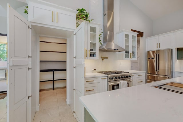 kitchen featuring white cabinets, light tile patterned floors, wall chimney exhaust hood, and high quality appliances