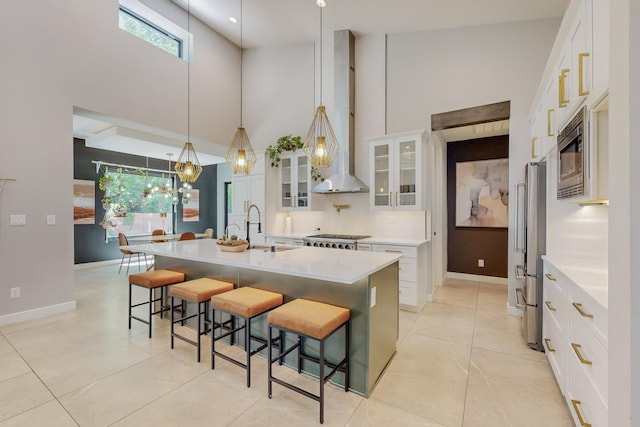 kitchen with sink, an island with sink, decorative light fixtures, a breakfast bar area, and white cabinets