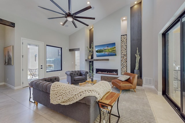 living room with a towering ceiling, ceiling fan, and light tile patterned flooring