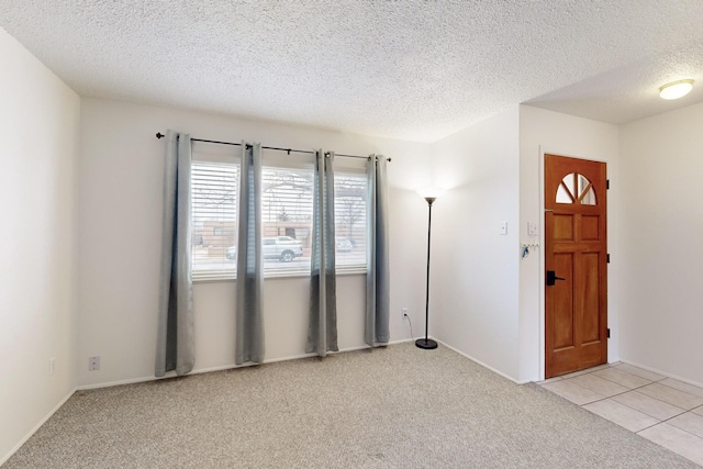 foyer entrance with light colored carpet and a textured ceiling