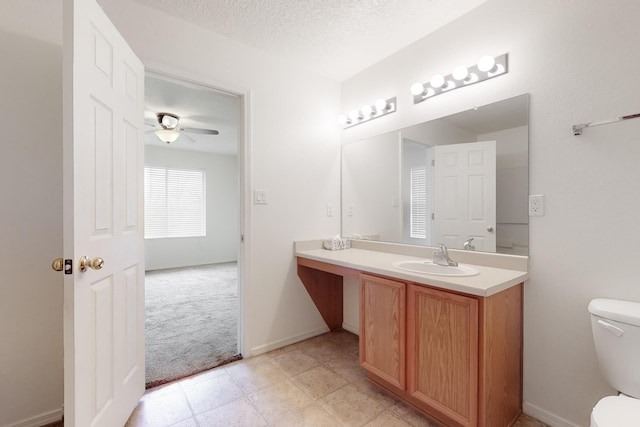 bathroom featuring a textured ceiling, toilet, ceiling fan, and vanity