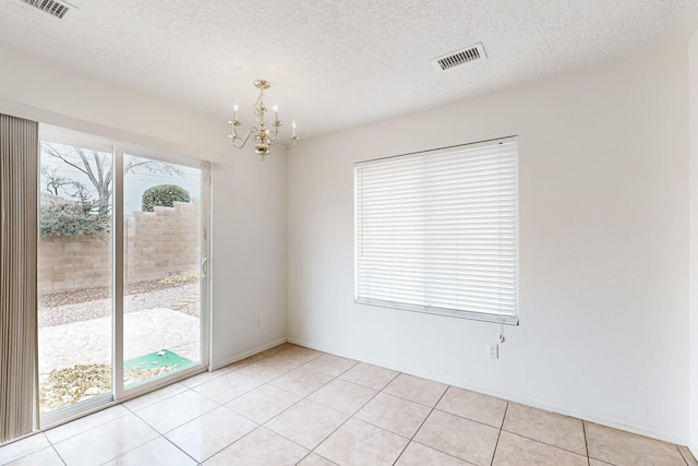 unfurnished room featuring an inviting chandelier, light tile patterned floors, and a textured ceiling