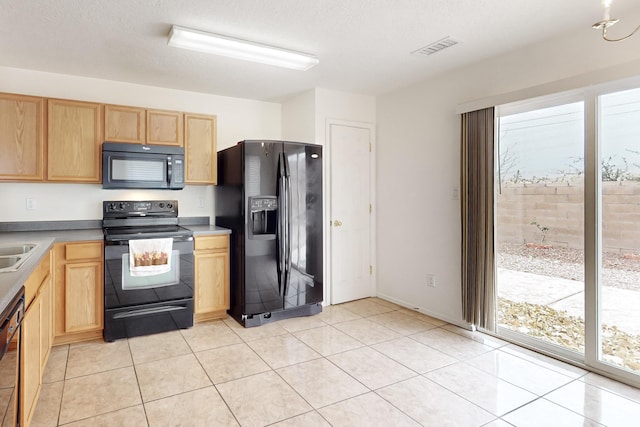 kitchen featuring light brown cabinetry, a textured ceiling, light tile patterned floors, and black appliances