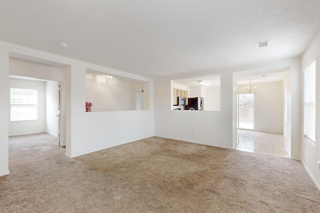 carpeted spare room featuring a textured ceiling and a chandelier