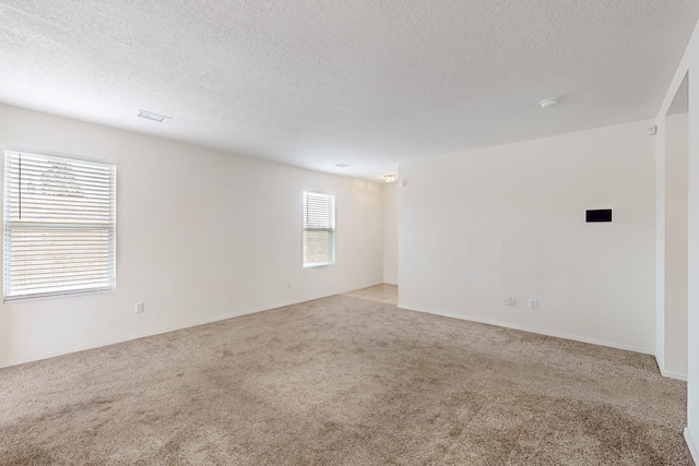 spare room with a textured ceiling and light carpet