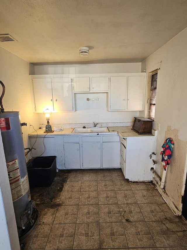 kitchen with sink, white cabinets, and gas water heater