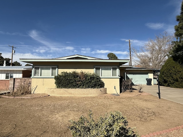 view of front of house with concrete driveway, an attached garage, and stucco siding