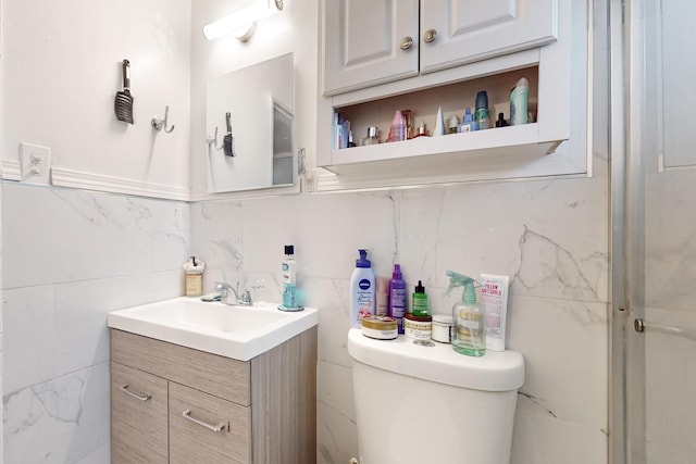 bathroom featuring toilet, tile walls, and vanity