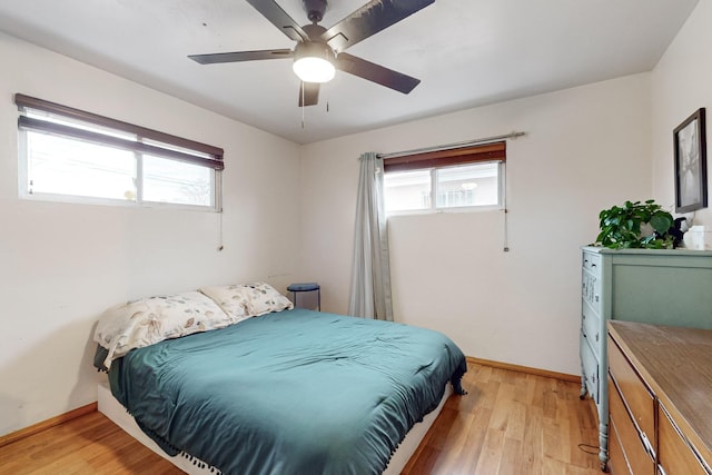 bedroom featuring ceiling fan, light wood-type flooring, and multiple windows