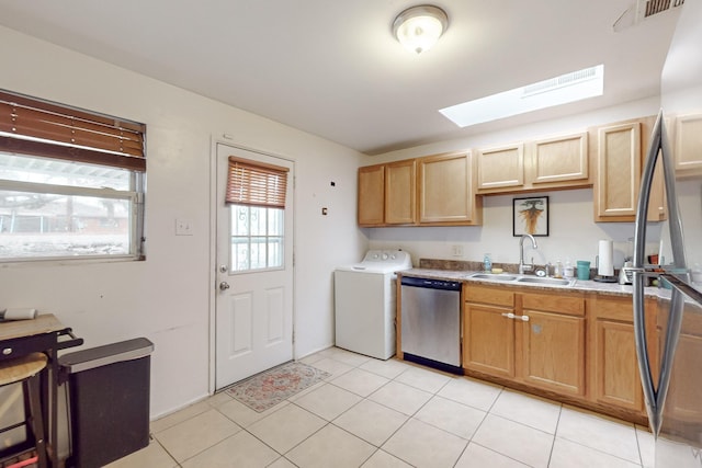 kitchen featuring light tile patterned floors, a skylight, stainless steel appliances, washer / clothes dryer, and sink