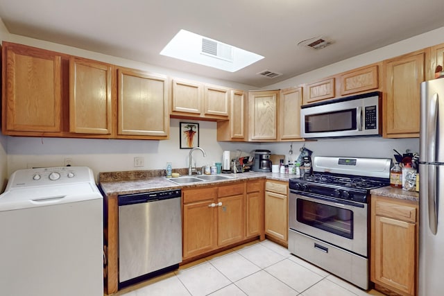 kitchen featuring washer / dryer, light tile patterned floors, a skylight, appliances with stainless steel finishes, and sink