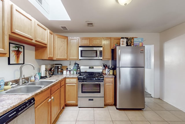 kitchen featuring light tile patterned floors, a skylight, appliances with stainless steel finishes, light brown cabinets, and sink