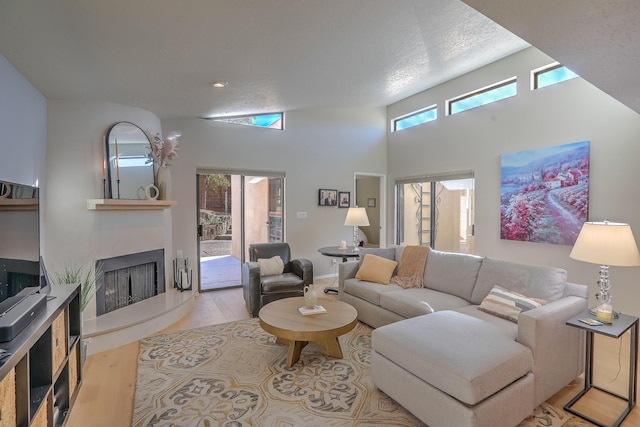 living room featuring a high ceiling, a textured ceiling, and light hardwood / wood-style floors