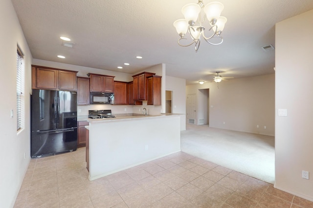 kitchen with kitchen peninsula, ceiling fan with notable chandelier, sink, black appliances, and hanging light fixtures