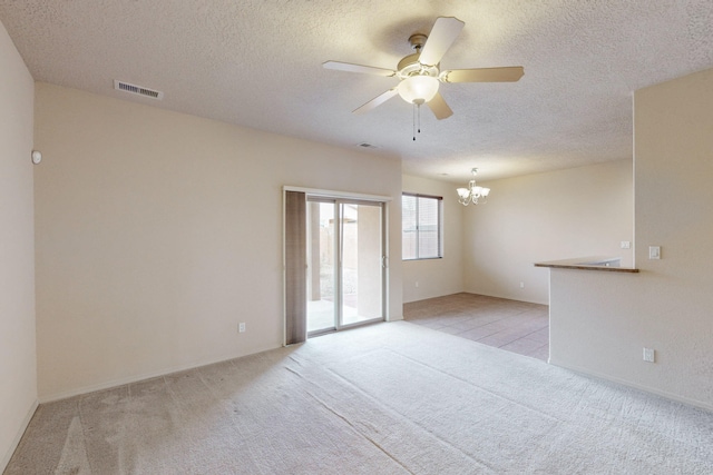 empty room with ceiling fan with notable chandelier, light colored carpet, and a textured ceiling