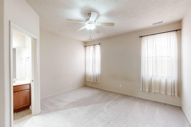 carpeted empty room with ceiling fan, sink, and a textured ceiling