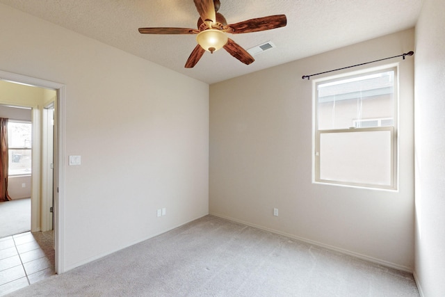 carpeted spare room with ceiling fan and a textured ceiling