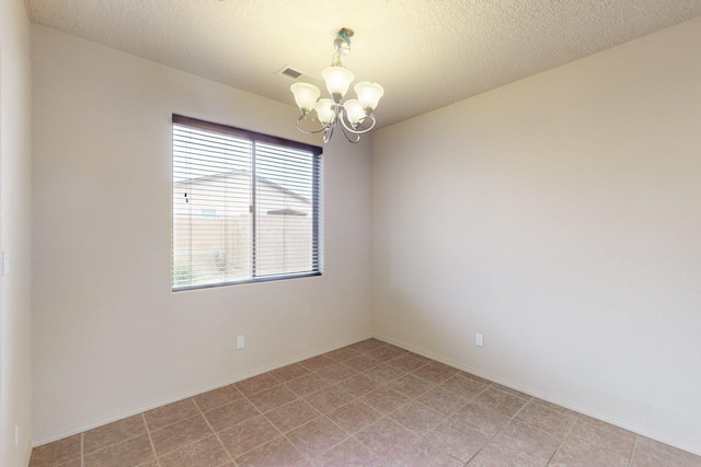 empty room with a textured ceiling and an inviting chandelier