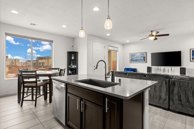 kitchen featuring sink, dishwasher, a healthy amount of sunlight, pendant lighting, and a kitchen island with sink