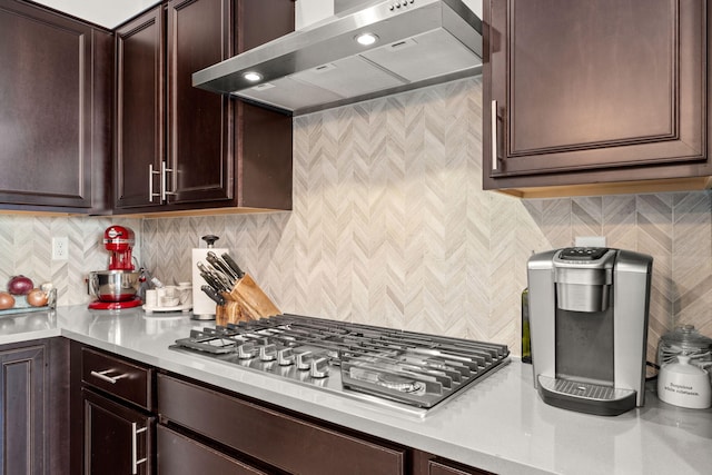 kitchen with tasteful backsplash, dark brown cabinetry, wall chimney exhaust hood, and stainless steel gas cooktop