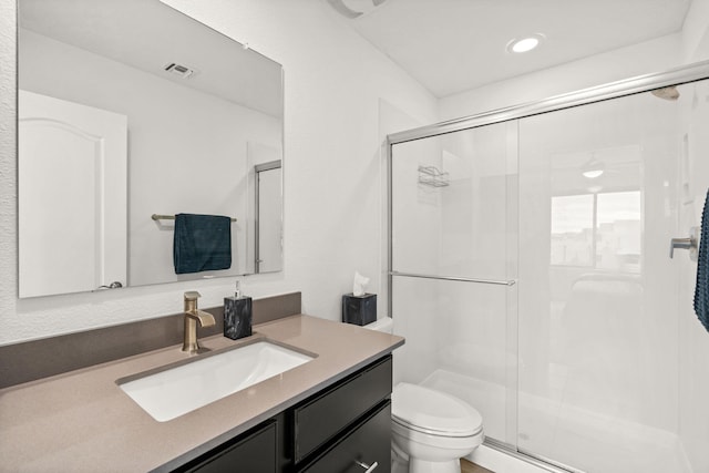 bathroom featuring vanity, a shower with shower door, and toilet