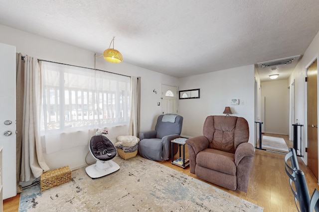 living area with a textured ceiling and hardwood / wood-style floors