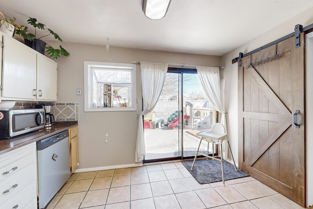 kitchen featuring white cabinets, light tile patterned flooring, a barn door, and appliances with stainless steel finishes