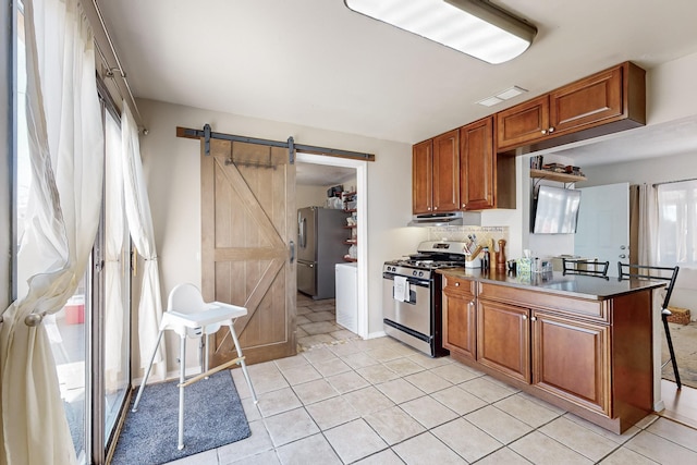 kitchen featuring sink, light tile patterned floors, a barn door, and appliances with stainless steel finishes