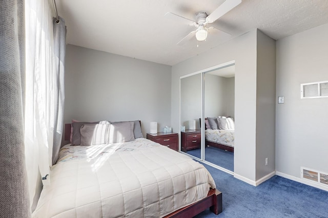 carpeted bedroom with a textured ceiling, ceiling fan, and a closet