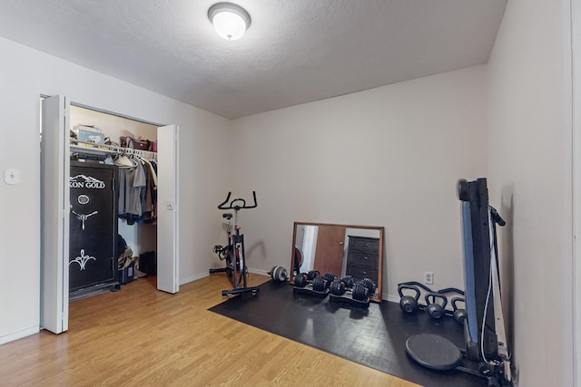 exercise room with a textured ceiling and light hardwood / wood-style floors