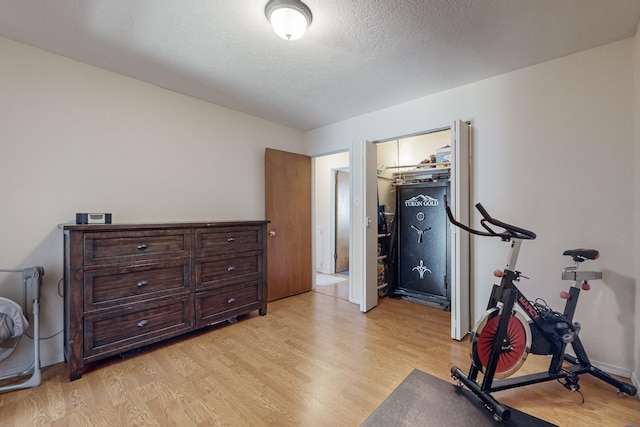 workout area featuring light hardwood / wood-style floors and a textured ceiling