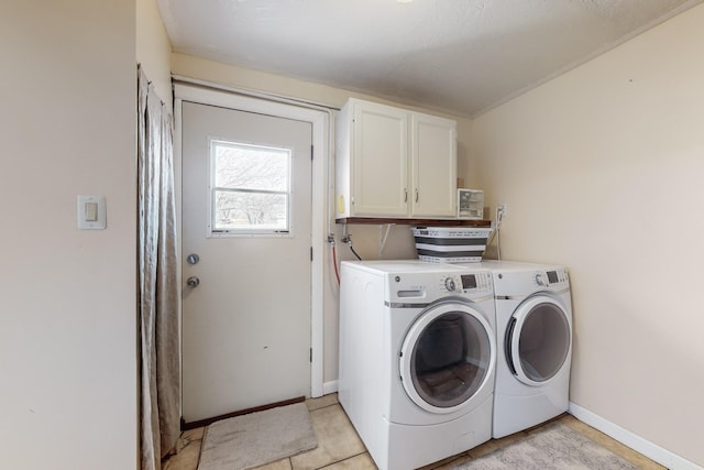 laundry room featuring light tile patterned floors, separate washer and dryer, and cabinets