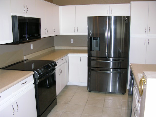 kitchen with black appliances, white cabinetry, and light tile patterned floors