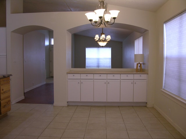 kitchen featuring white cabinets, light tile patterned floors, hanging light fixtures, and a notable chandelier