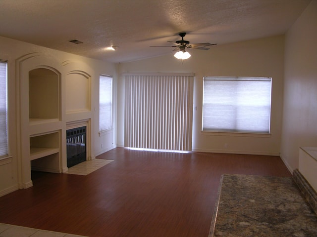 unfurnished living room with ceiling fan, lofted ceiling, a textured ceiling, a fireplace, and light wood-type flooring