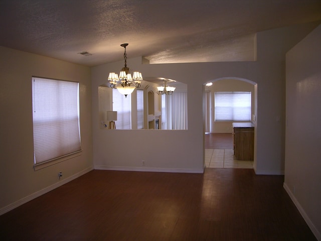 spare room with dark hardwood / wood-style flooring, lofted ceiling, a textured ceiling, and a chandelier