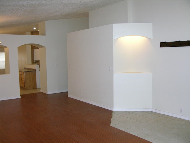 unfurnished room featuring a textured ceiling and high vaulted ceiling