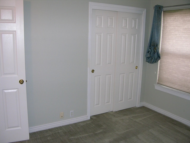 unfurnished bedroom with dark colored carpet and a closet