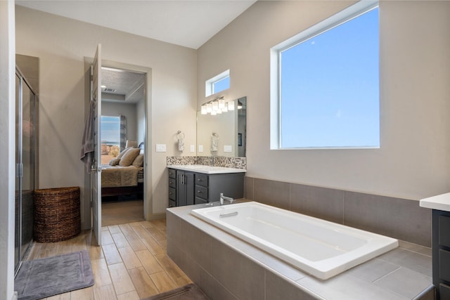 bathroom with vanity, a wealth of natural light, and tiled tub