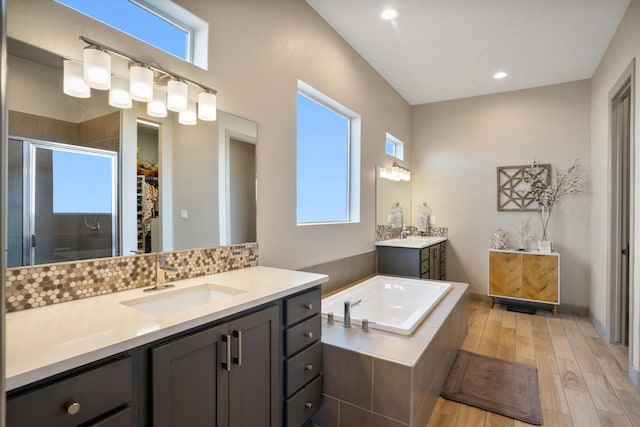 bathroom with independent shower and bath, hardwood / wood-style floors, and vanity