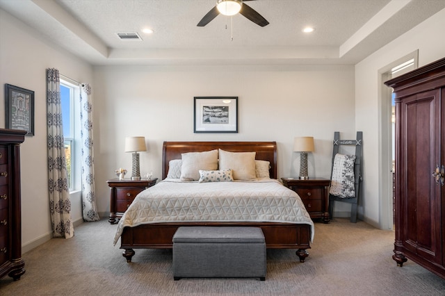 bedroom with a raised ceiling, ceiling fan, and light carpet