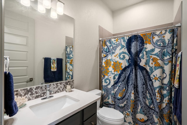 bathroom with toilet, vanity, decorative backsplash, and walk in shower