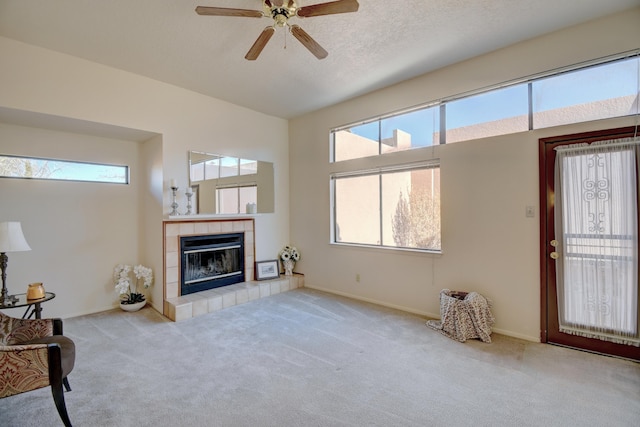 living room with ceiling fan, a fireplace, light colored carpet, and a textured ceiling