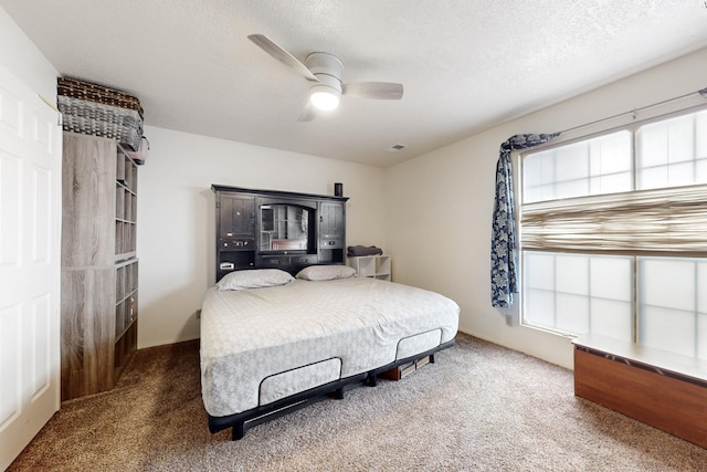 bedroom with dark colored carpet, a textured ceiling, and ceiling fan