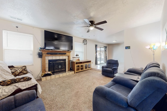 living room with a fireplace, a textured ceiling, carpet floors, and ceiling fan