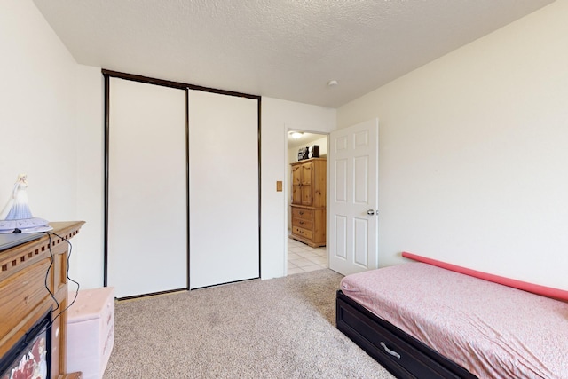 carpeted bedroom with a textured ceiling and a closet