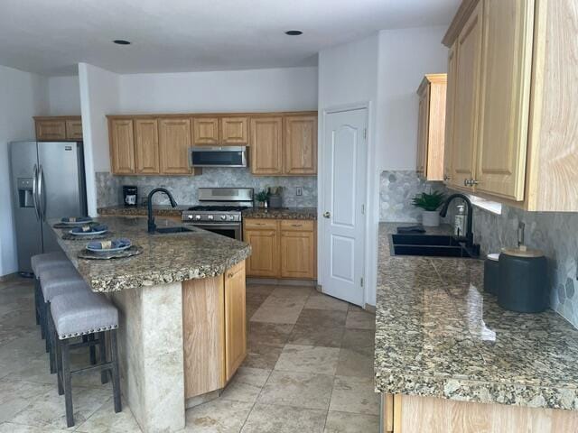 kitchen with stainless steel appliances, a sink, decorative backsplash, and a breakfast bar area