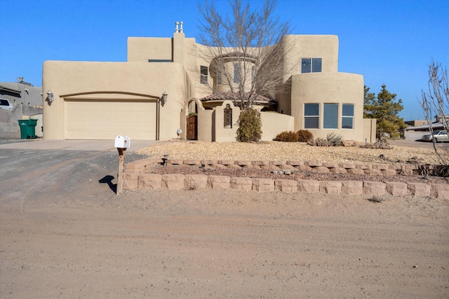 southwest-style home with driveway, stucco siding, an attached garage, and fence