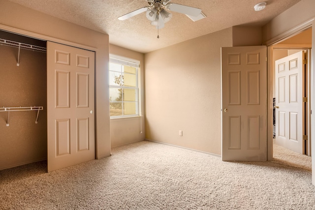 unfurnished bedroom with carpet flooring, ceiling fan, a closet, and a textured ceiling