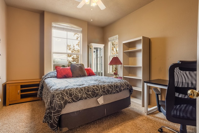 carpeted bedroom featuring ceiling fan and a textured ceiling